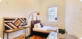 a bedroom with a desk, a bed and a lamp
